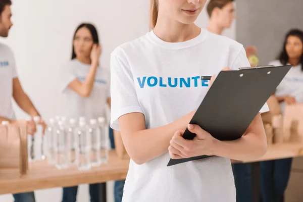 Volunteer writing in clipboard — Stock Photo