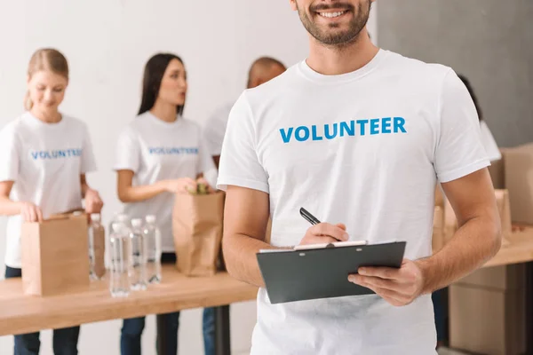 Volunteer writing in clipboard — Stock Photo