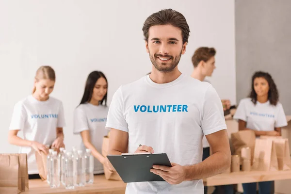 Volunteer writing in clipboard — Stock Photo