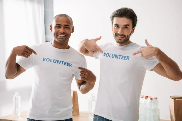 Volunteers pointing at signs on t-shirts — Stock Photo