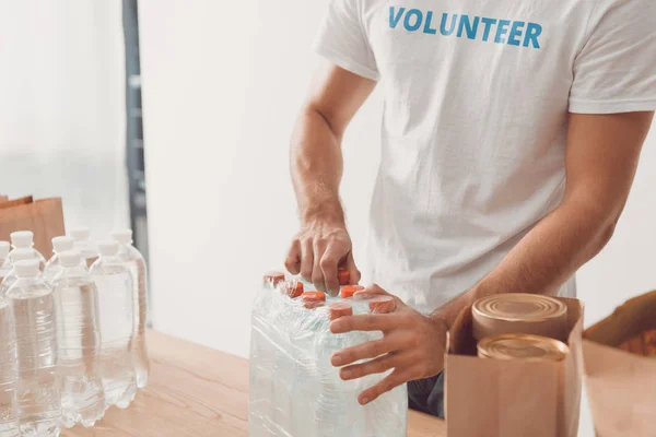 Volunteer opening pack of water bottles — Stock Photo