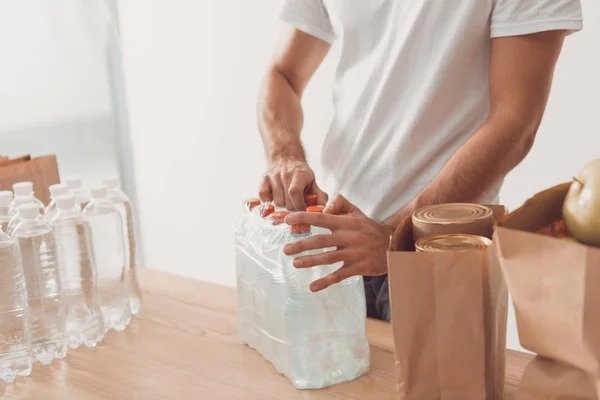 Volunteer opening pack of water bottles — Stock Photo