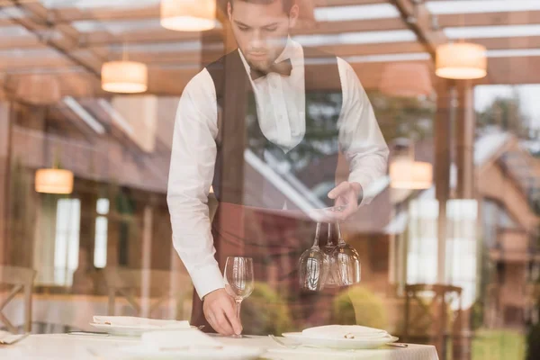 Camarero poniendo anteojos de vino en la mesa - foto de stock