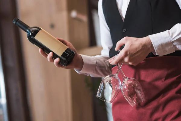 Camarero sosteniendo botella y gafas de vino - foto de stock