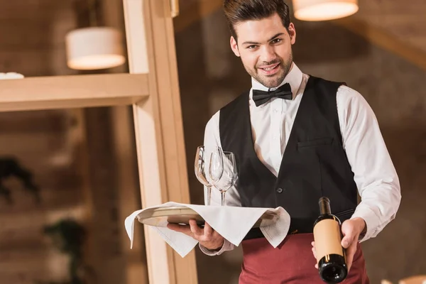 Camarero sosteniendo gafas de vino y botella - foto de stock