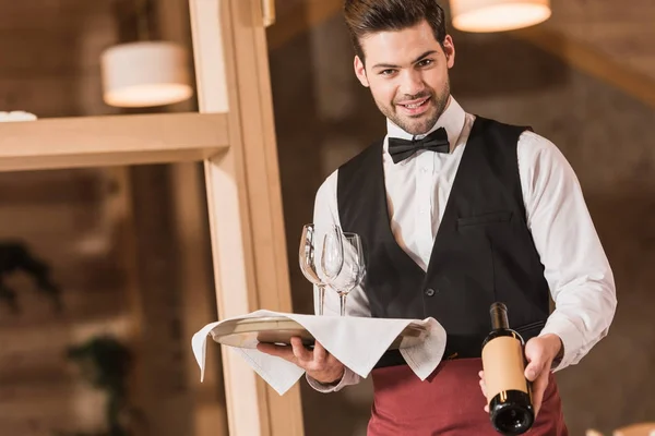 Garçom segurando vinhos e garrafa — Fotografia de Stock