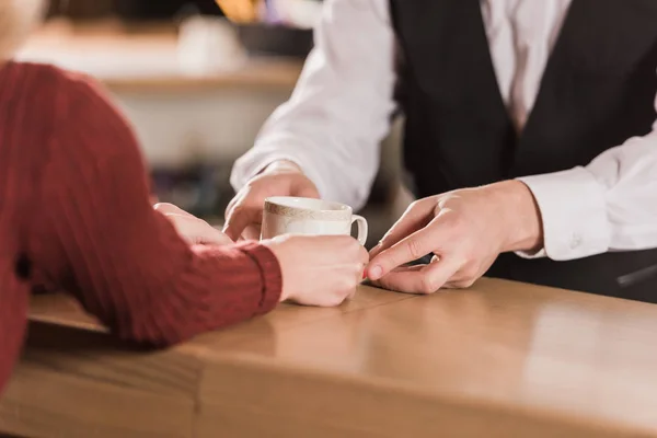 Camarero dando taza de café al cliente - foto de stock