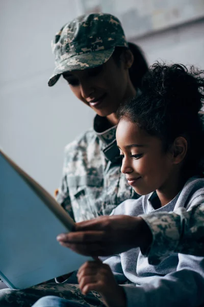 Hija y soldado leyendo libro - foto de stock