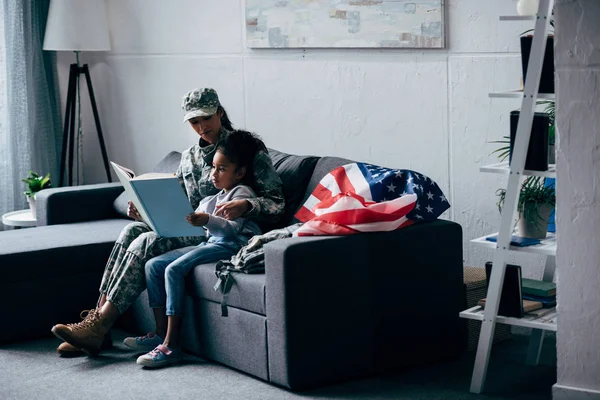 Daughter and soldier reading book — Stock Photo