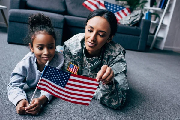 Hija y soldado con bandera americana - foto de stock