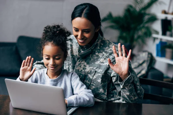 Mujer en uniforme militar e hija con portátil - foto de stock