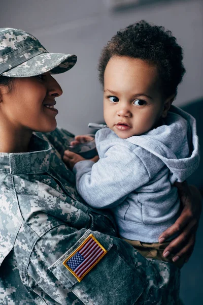 Madre en uniforme militar con hijo pequeño - foto de stock