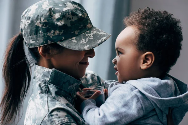 Madre en uniforme militar con hijo pequeño - foto de stock