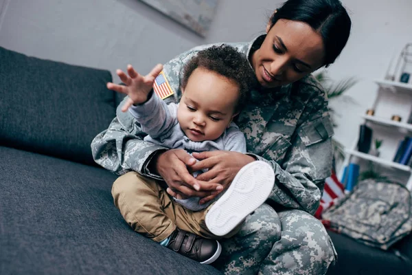 Madre en uniforme militar con hijo pequeño - foto de stock
