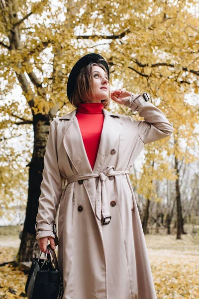 Woman in trench coat at autumn park — Stock Photo