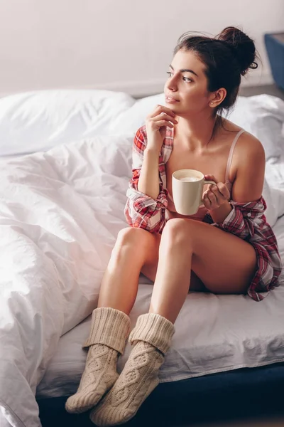 Fille rêveuse en chaussettes tricotées avec café — Photo de stock