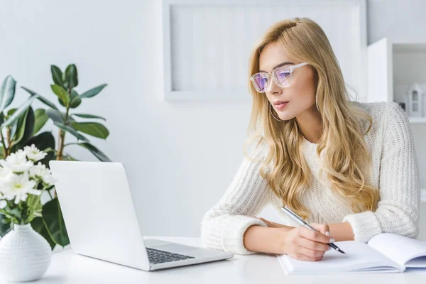 Blonde businesswoman writing and workig with laptop — Stock Photo