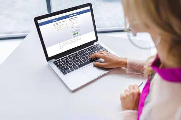 Woman using laptop with facebook — Stock Photo