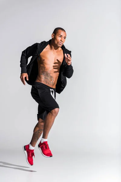 Handsome young african american sportsman running on grey — Stock Photo