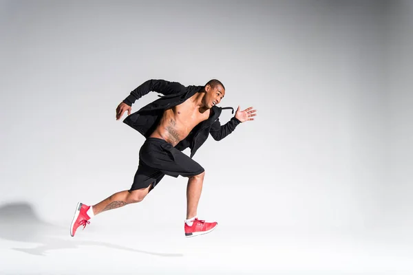 Joven deportista afroamericano corriendo sobre gris - foto de stock