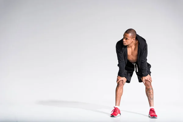 Full length view of young african american sportsman in hoodie and sneakers looking away on grey — Stock Photo