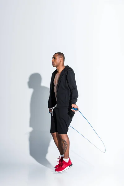 Молодий афроамериканець спортсмен вправи зі скакалкою на сірому — стокове фото