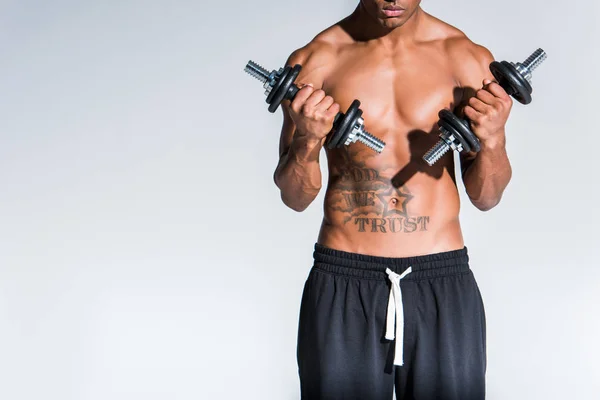 Tiro recortado de desportista afro-americano sem camisa exercitando com halteres isolados em cinza — Fotografia de Stock