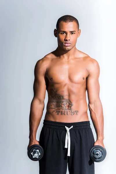 Atletico sportivo afroamericano senza maglietta con manubri che guarda la macchina fotografica isolata sul grigio — Foto stock