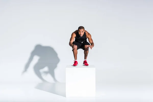 Volle Länge Ansicht des jungen afrikanisch-amerikanischen Sportler springen und Blick auf Kamera auf grau — Stockfoto