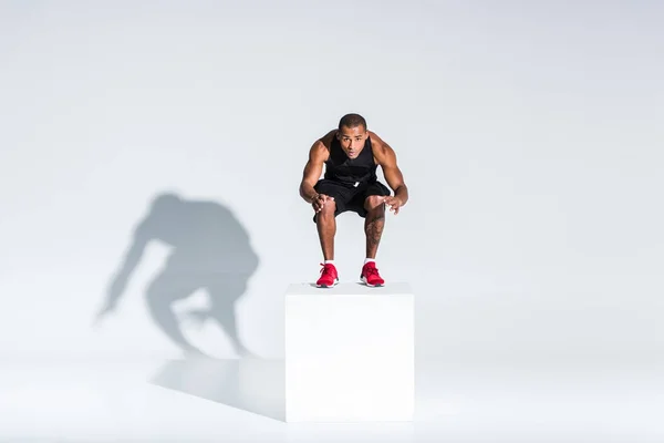 Full length view of young african american sportsman jumping and looking at camera on grey — Stock Photo