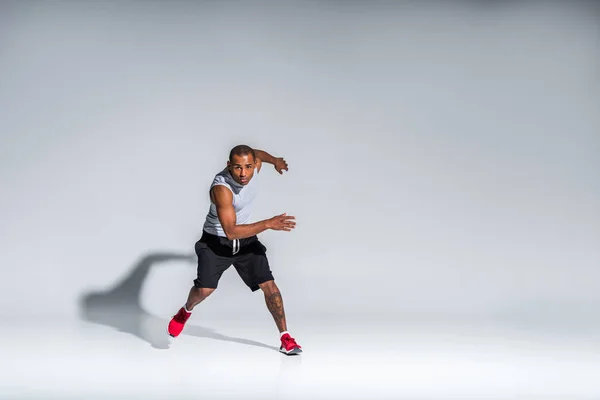 Vista completa del atlético joven afroamericano deportista mirando a la cámara en gris - foto de stock