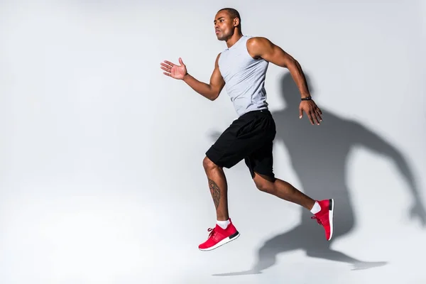 Atlético joven afroamericano deportista corriendo en gris - foto de stock