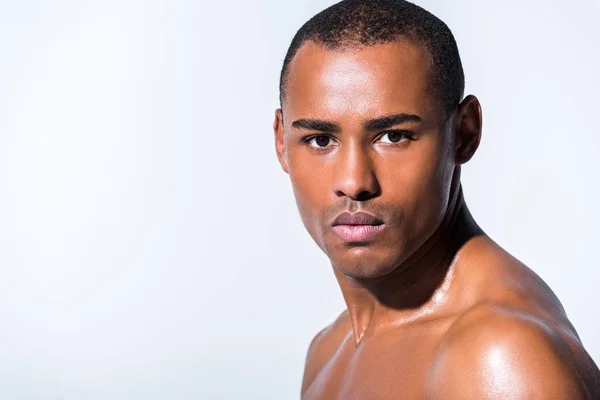 Close-up portrait of young shirtless african american man looking at camera isolated on grey — Stock Photo