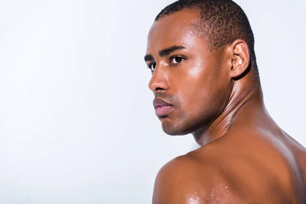 Retrato de un apuesto deportista afroamericano sin camisa mirando hacia otro lado aislado en gris - foto de stock