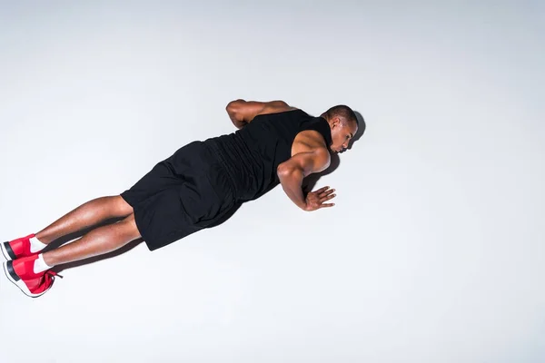 High angle view of young african american sportsman doing push ups isolated on grey — Stock Photo