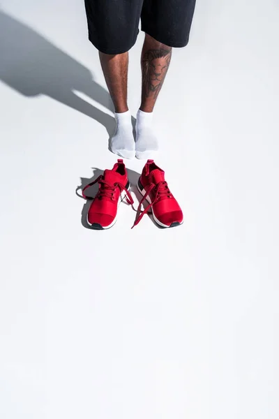 Vista de ángulo alto del deportista en calcetines y zapatos deportivos rojos en gris - foto de stock