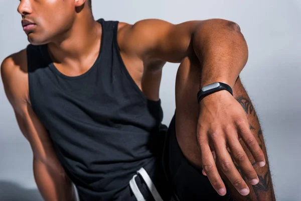Tiro recortado de jovem esportista afro-americano vestindo rastreador de fitness em cinza — Fotografia de Stock