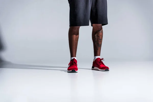 Low section of african american man in sports shoes on grey — Stock Photo