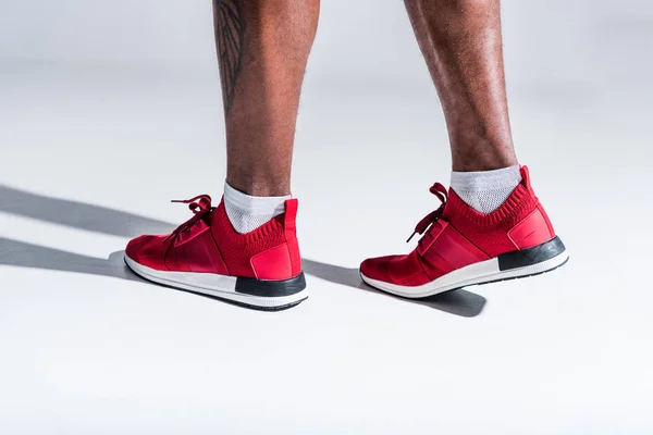 Cropped shot of african american man in sports shoes on grey — Stock Photo