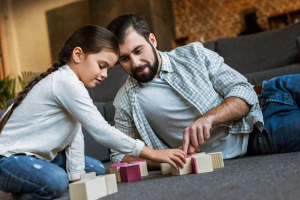 Padre allegro con figlia che fa parole da cubi con lettere a casa — Foto stock