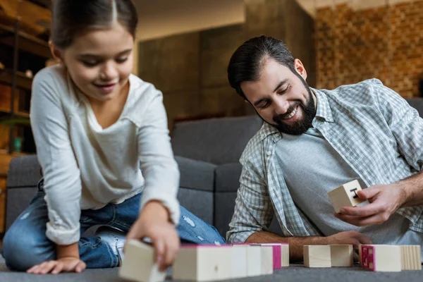 Веселий батько з дочкою робить слова кубиками з літерами вдома — стокове фото