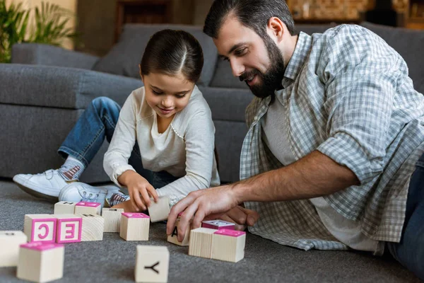 Cheerful father with daughter making words by cubes with letters at home — Stock Photo