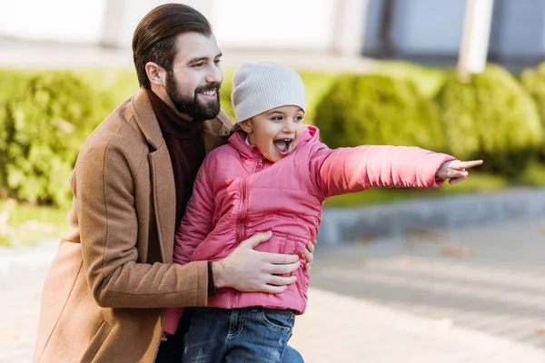 Happy father with daughter hugging and pointing on something. outside — Stock Photo