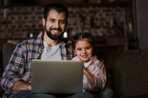 Happy father with daughter sitting on couch and using laptop — Stock Photo