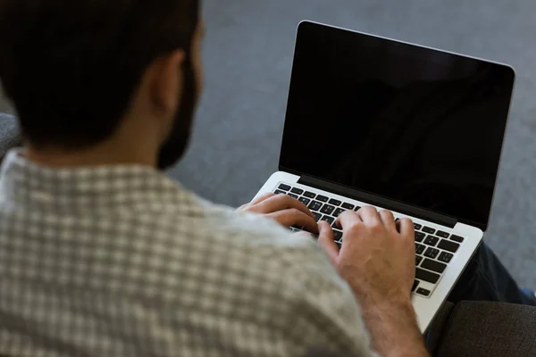 Vista posteriore di uomo seduto sul divano e utilizzando il computer portatile — Foto stock