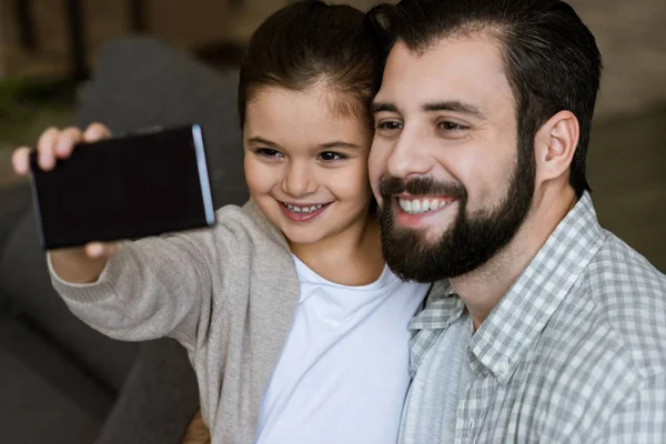 Padre allegro con figlia che prende selfie sullo smartphone a casa — Foto stock