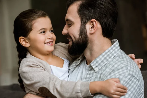 Allegro padre e figlia che si abbracciano e si guardano a casa — Foto stock