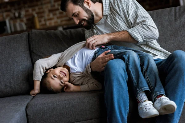 Vater mit Tochter liegt auf Couch, umarmt und lacht zu Hause — Stockfoto