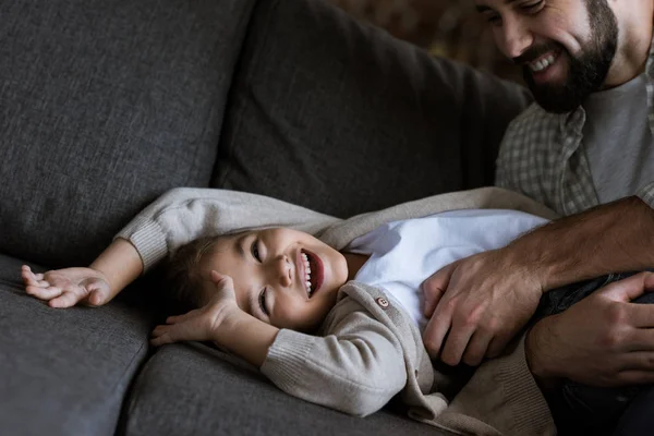 Vater mit Tochter liegt auf Couch, umarmt und lacht zu Hause — Stockfoto