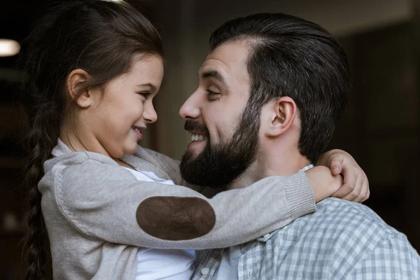 Fröhlicher Vater und Tochter, die sich zu Hause umarmen und anschauen — Stockfoto